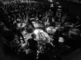 A packed intimate venue with musicians performing on stage amid a dense crowd.