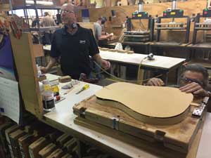 A Gibson factory working making sure that the top aligns just right with the rest of the body.