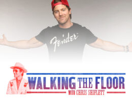 A man in a red baseball cap wears a Fender t-shirt with his arms stretched wide.