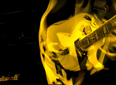 Yellow electric guitar played during performance, captured in warm stage lighting.