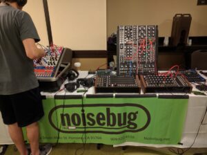 A person tests modular synthesizers at the Noisebug electronic music equipment booth.