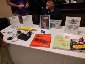 A table displays electronic kits, books, instructional documents, and hardware components for maker projects.