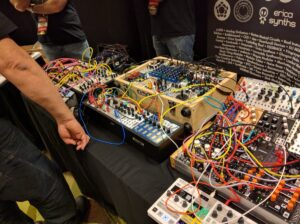Modular synthesizer circuits with colorful patch cables interconnected on display.
