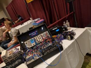 A modular synthesizer with colorful patch cables and multiple modules sits on a white table.