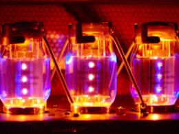 Three vacuum tubes glow with blue and orange light against a red background.