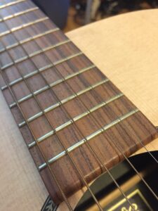 Old tarnished guitar strings on a neck showing oxidation and darkening from age.