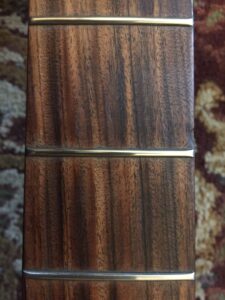 A guitar neck showing worn and darkened frets with visible patina and wear patterns.