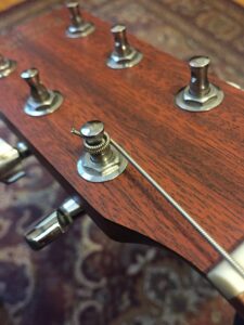 A guitar headstock showing multiple tuning pegs and one prominently wound string.