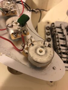 Interior wiring components of a guitar showing potentiometers and connecting wire harnesses.