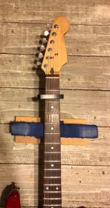 A guitar neck with a capo clamped across the fretboard.
