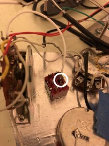 Close-up of electrical wiring with a center lug connector in a white circle.