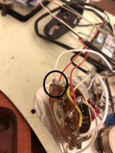 Close-up of switch wiring with a copper lug connector circled in black.