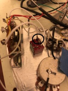 Close-up of electrical wiring with a red lug connector highlighted in a black circle.