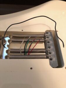 Bass bridge assembly featuring four coiled springs with colored wires for electronic connections.
