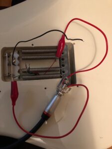 Heating element with four coiled wire loops and red electrical connecting wires.