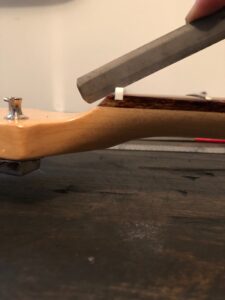 A straight edge held against a guitar neck demonstrates a steep string angle.