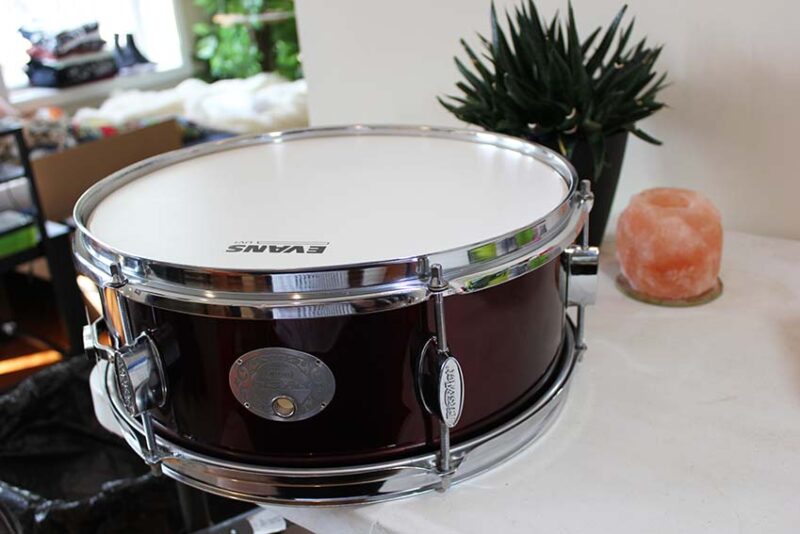 Completed black snare drum with white head and chrome hardware.