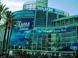 The NAMM convention center exterior features prominent signage and palm trees under a bright blue sky.