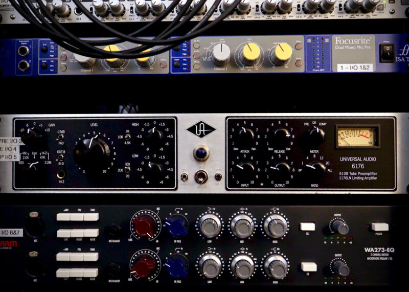 Professional audio equipment including Focusrite and Universal Audio units stacked in a rack.