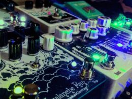 Close-up of DJ equipment with illuminated knobs and faders glowing green and blue.