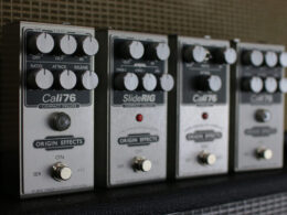Four Origin Effects guitar pedals including Cali76 and SlideRIG arranged in a row.