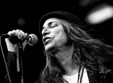 A long-haired performer sings into an SM58 microphone during a concert.