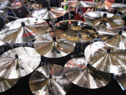 Multiple bronze and brass cymbals stand mounted on black stands for a drum kit.