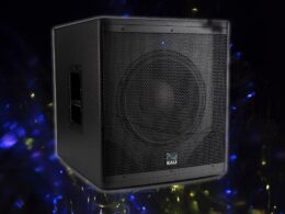 Black Kali audio speaker with perforated grille surrounded by blue and yellow bokeh lights on dark background.