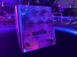 Neon-illuminated Eventide Ultra Tap guitar effect pedal glowing purple and blue surrounded by dark studio equipment.