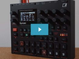 A black Syntakt drum computer and synthesizer with illuminated buttons, knobs, and numbered pads on wood.