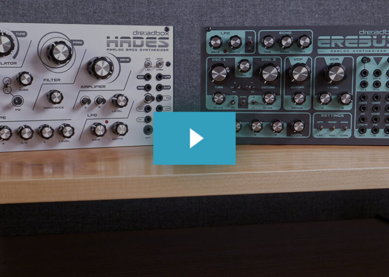 Light Hades and dark Erebus Dreadbox synthesizer modules sit side by side on a wooden desk.