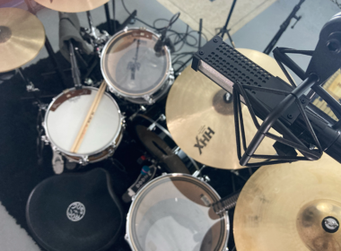 Overhead view of a professional drum kit with black drums and multiple cymbal stands.