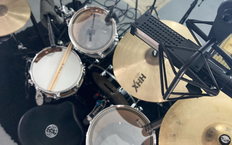Overhead view of a professional drum kit with black drums and multiple cymbal stands.