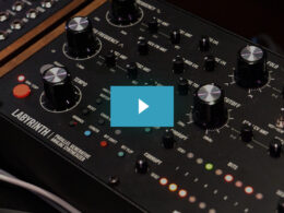 The Moog Labyrinth synthesizer displays multiple black knobs, colored button controls, and a wooden accent panel.