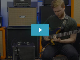 Musician plays yellow bass guitar in professional studio surrounded by cream-colored Laney amplifiers.