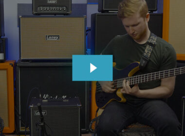 Musician plays yellow bass guitar in professional studio surrounded by cream-colored Laney amplifiers.