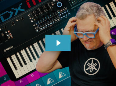 Man wearing blue glasses poses beside a Yamaha MODX-M synthesizer keyboard on a dark background.