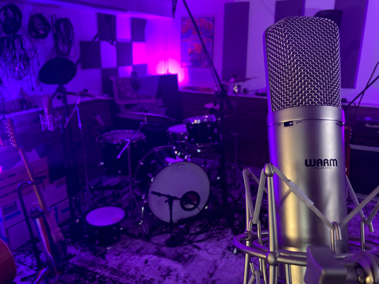 A large professional microphone stands in a dark recording studio bathed in purple and blue neon.