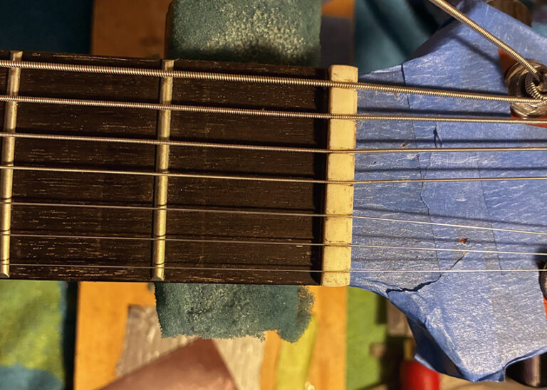 Close-up of a 7-string guitar headstock showing tuning pegs, multiple strings, and part of the fretboard.