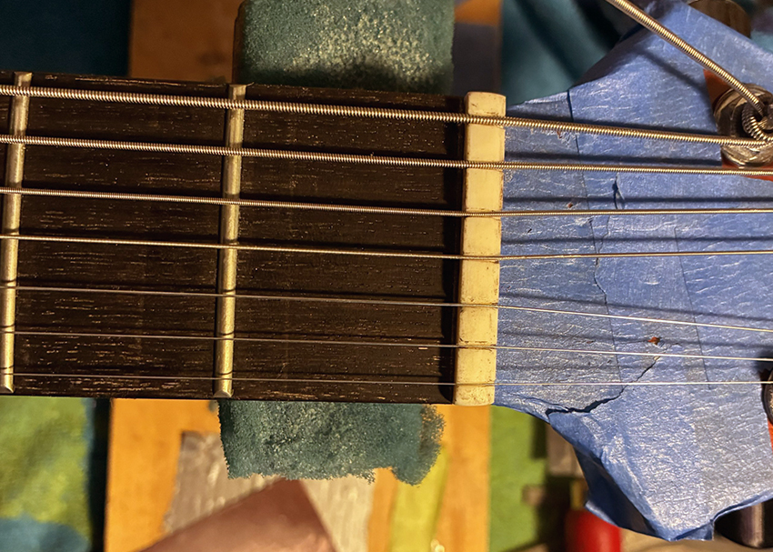 Close-up of a 7-string guitar headstock showing tuning pegs, multiple strings, and part of the fretboard.